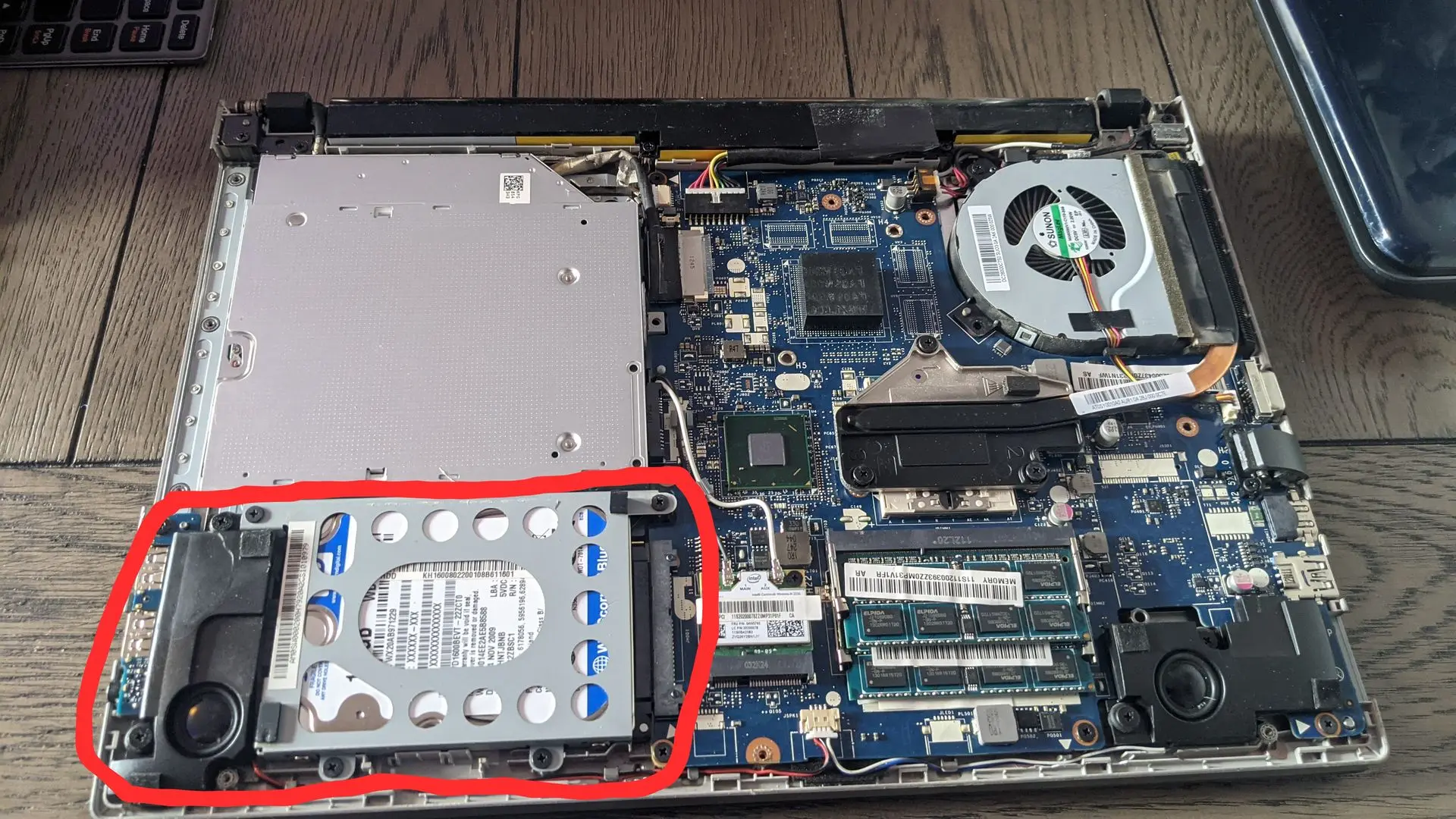 Internal view of a laptop during repair or diagnostics. An open laptop showing the internal components including RAM sticks, cooling fan, motherboard, and heat sink, representing computer repair or diagnostics.