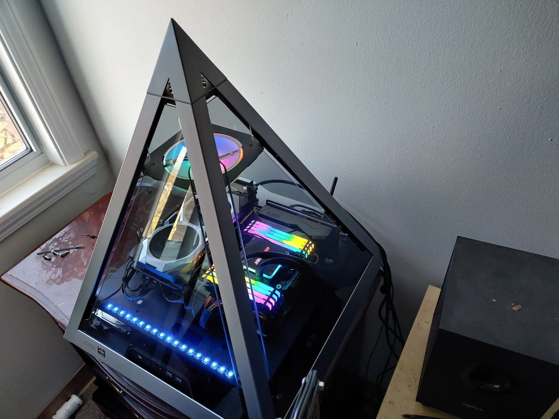 Custom-built gaming PC with RGB lighting and glass case. A custom-built desktop gaming PC with RGB lighting and a unique triangular glass case design, showcasing internal components and cooling.